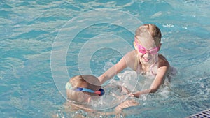 Little boy and girl swimming in swimming pool, children having fun, splashing water. Summer travel family hotel vacation