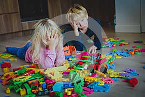 Little boy and girl tired stressed exhausted with toys scattered indoors