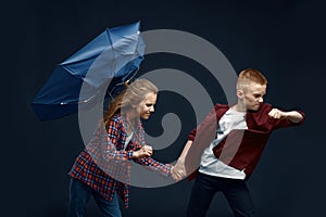 Little boy and girl with umbrella against airflow