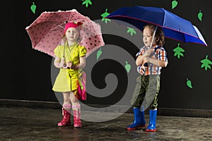 Little boy and girl with umbrellas in bright