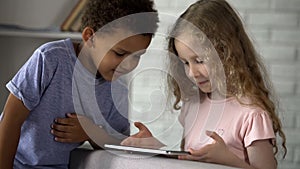 Little boy and girl watching movie on tablet at kindergarten, early development