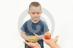 The little boy is given a choice of hamburger or apple. The concept of choosing the right food, healthy lifestyle, fast food is
