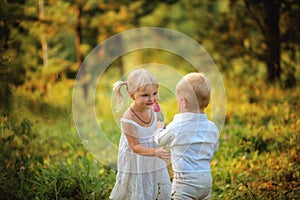 Little boy gives a flower to a little girl in the wood