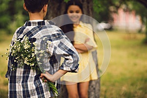 Little boy giving bouqet of flowers to girl.