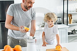 little boy giving father orange for making fresh juice