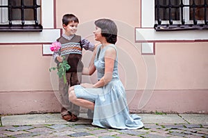 Little boy giving flower to his mom