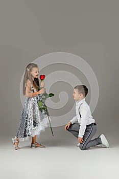 Little boy giving a red rose to child girl