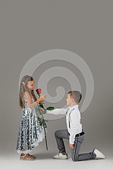 Little boy giving a red rose to child girl