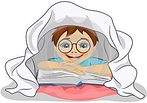 Little boy with glasses reads a book in bed under blanket