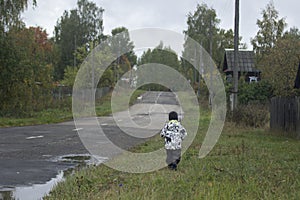 A little boy going along the road in a russian village