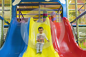 Little boy is going down a slide at the playground. He is laughing and having fun on the jungle gym. Boy riding from childrens