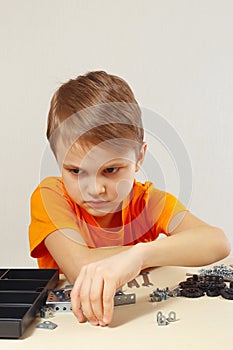 Little boy is going to play with mechanical kit at table