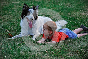 Little Boy in the Grass With a Dog both Sticking Out Their Tongues