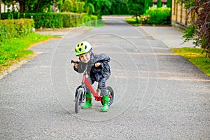 Little boy in green helmet and balance bike run bike. Childho