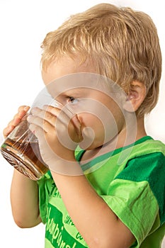 Little boy in a green T-shirt happily drinking tea