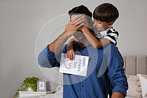 Little boy greeting his dad with Father`s Day at home