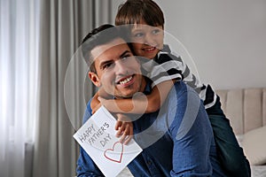 Little boy greeting his dad with Father`s Day at home