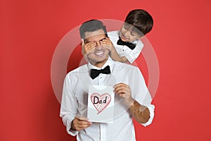 Little boy greeting his dad with Father`s Day on red background