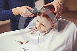 Little boy at the hairdresser. Child is scared of haircuts. Hair