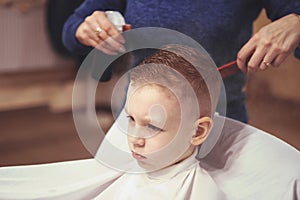 Little boy at the hairdresser. Child is scared of haircuts. Hair