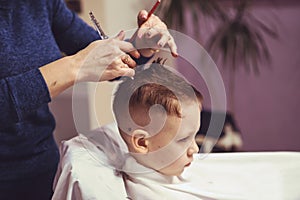 Little boy at the hairdresser. Child is scared of haircuts. Hair