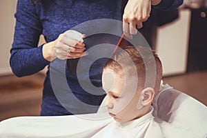 Little boy at the hairdresser. Child is scared of haircuts. Hair