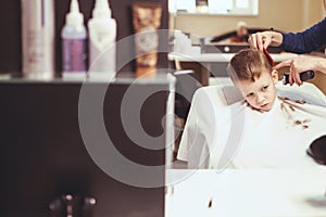 Little boy at the hairdresser. Child is scared of haircuts. Hair