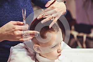 Little boy at the hairdresser. Child is scared of haircuts. Hair