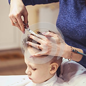 Little boy at the hairdresser. Child is scared of haircuts. Hair