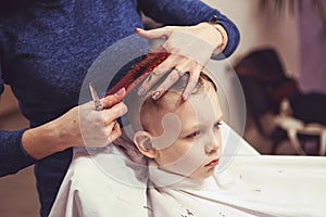 Little boy at the hairdresser. Child is scared of haircuts. Hair