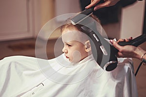 Little boy at the hairdresser. Child is scared of haircuts. Hair