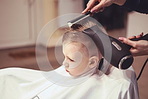 Little boy at the hairdresser. Child is scared of haircuts. Hair