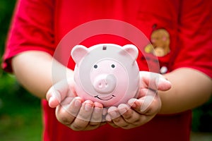 Little boy hand holding piggy bank with copy space