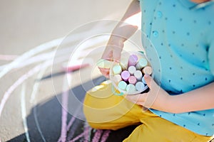 Little boy hands holding box with colorful chalks with drawing on background