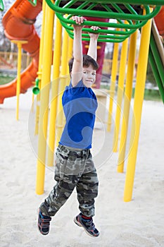 Little boy hanging on jungle gym