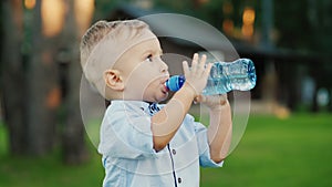 The little boy has been drinking water from the bottle for 1 year. Standing in the backyard of your house