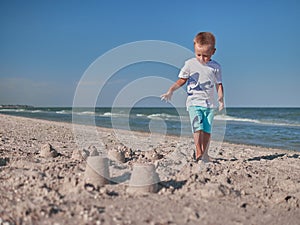 Little boy having on beach fun with the sand. Baby playing on the seaside in summertimes. Summer rest concept. Happy