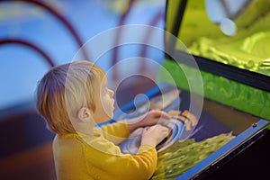 Little boy having fun in amusement in play center. Kid playing on slot machine in Arcade centre