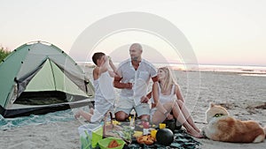 Little boy having fun with apples on picnic with parents and dog on the beach