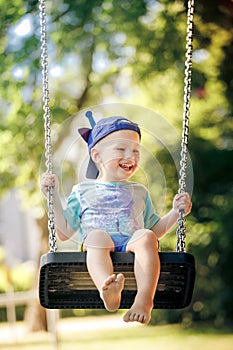 Little boy having fun on chain swing on the playground