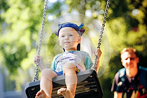 Little boy having fun on chain swing on the playground