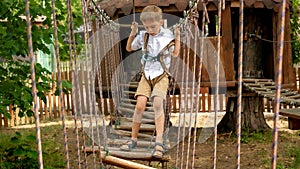 Little boy having fun at extreme adventure park in summer camp. Kids sports, summer holiday, fun outdoors, scouts