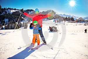 Little boy having fun with his attractive father during skiing in Alps.