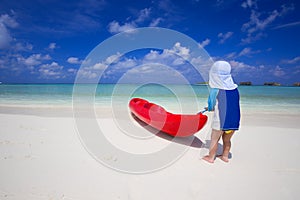 Little boy having fun with kayak in tropical lagoon