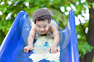 Little boy having fun on a playground outdoors in summer.