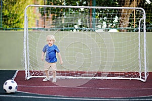 Little boy having fun playing a soccer/football game on summer day