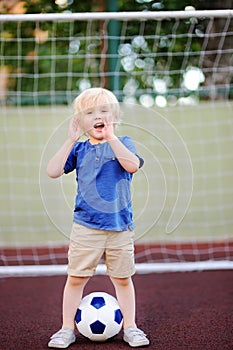 Little boy having fun playing a soccer/football game on summer day