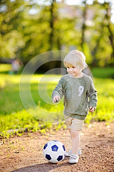 Little boy having fun playing a soccer/football game on summer day