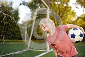 Little boy having fun playing a soccer/football game on summer day. Active outdoors game/sport for children