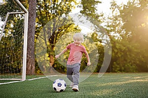 Little boy having fun playing a soccer/football game on summer day. Active outdoors game/sport for children